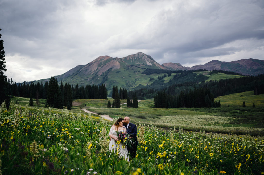 A couple hugs during their Crested butte elopement surrounded by wildflowers.